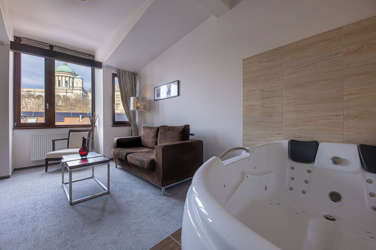 Une chambre moderne dotée d’une grande fenêtre, d’un canapé, d’une table basse et d’un jacuzzi.