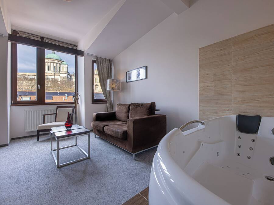 A modern room with a large window, a sofa, a coffee table, and a jacuzzi tub.