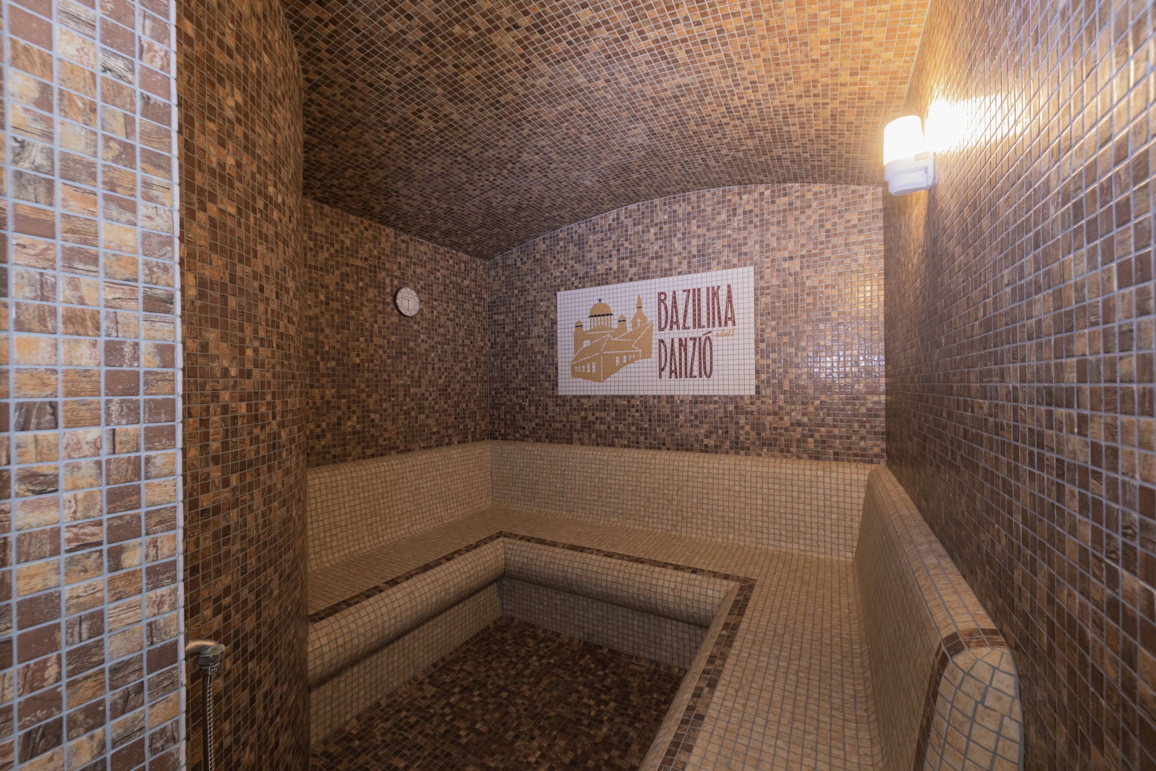A tiled bathroom with a sign reading "BAZILIKA PANZIO".