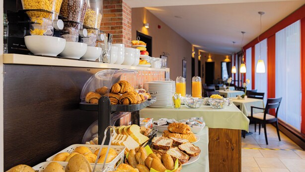 Un buffet proposant divers produits pour le petit-déjeuner, notamment du pain, des viennoiseries et des boissons.