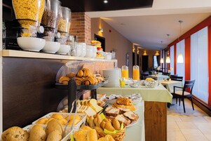 Buffet com diversas opções de pequeno-almoço, incluindo pão, pastelaria e bebidas.