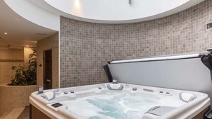 Un bain à remous dans une salle de bain moderne, avec un mur carrelé et un plancher en bois.