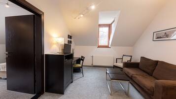 A compact living space with a kitchenette, a sofa, a dining table, and a window with a view.