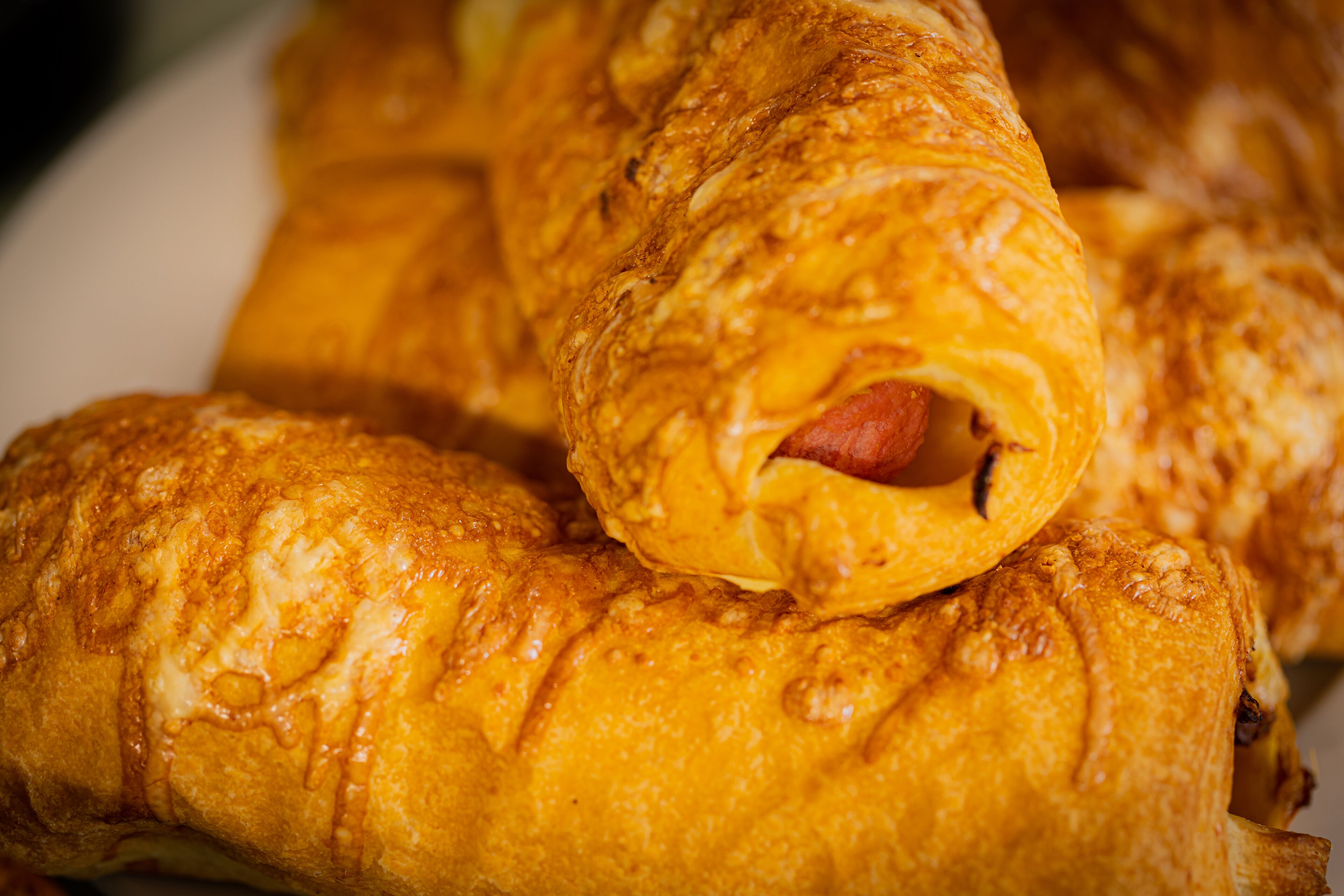 A close-up of a plate with golden-brown pastries, likely croissants, with visible fillings.