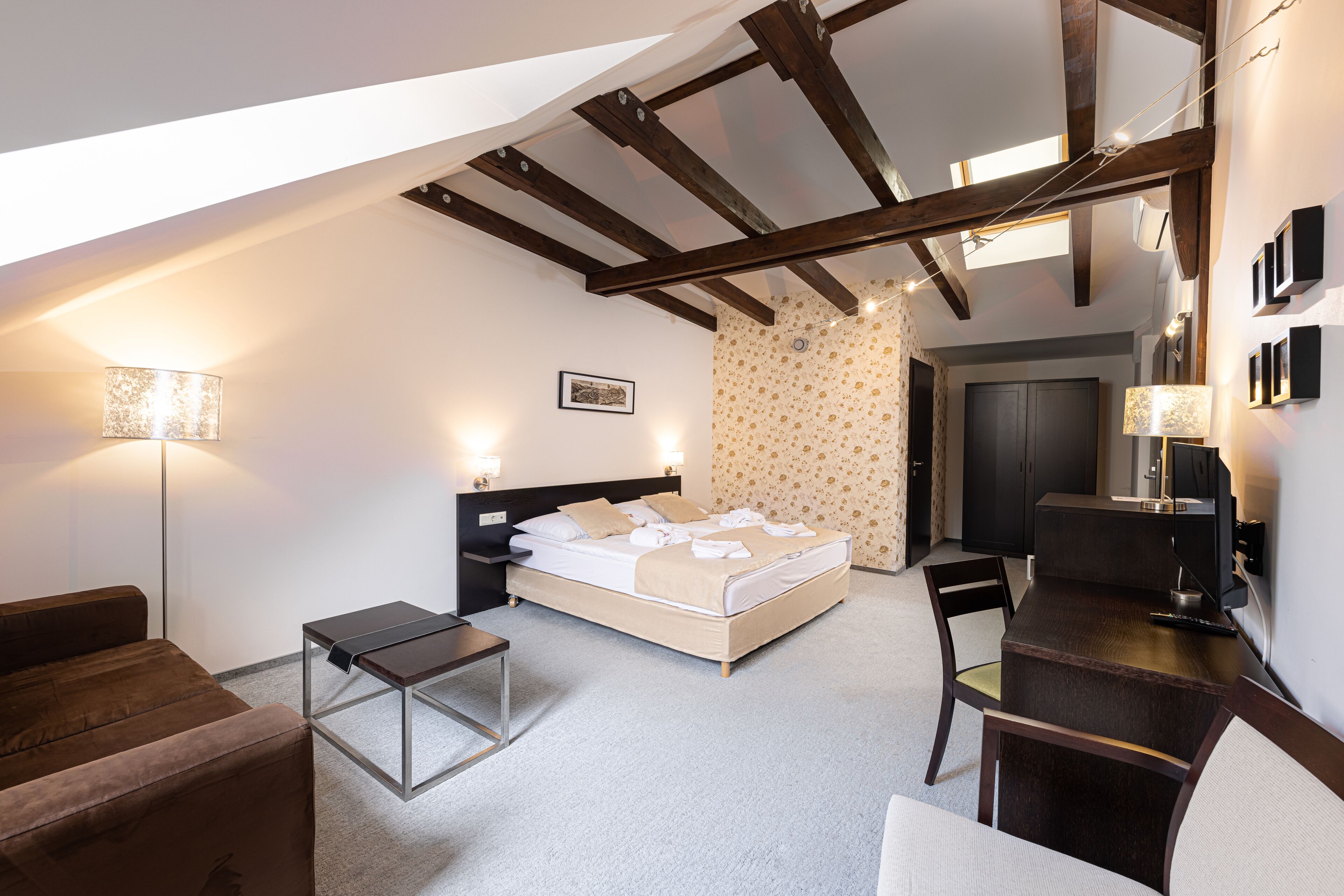 A bedroom with a bed, bedside tables, a desk, and a chair. There is a window with a view of the outside.