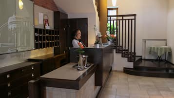 A hotel reception area with a counter, a staircase, and a view of the cityscape.