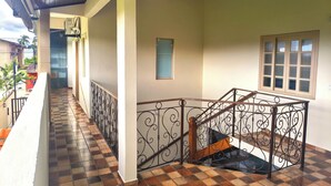 A covered outdoor corridor with tiled flooring, a staircase with ornate metal railings, and a view of the surrounding buildings. - Pousada Solar do Jabaquara (Paraty)