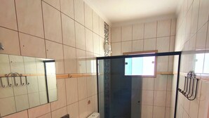 A bathroom with a granite countertop sink, a toilet, a glass shower enclosure, and a mirror. - Pousada Solar do Jabaquara (Paraty)