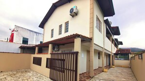 A two-story house with a stone-tiled patio, a gated entrance, and a covered porch. - Pousada Solar do Jabaquara (Paraty)
