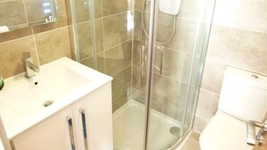 Une salle de bain avec une douche à parois de verre, un lavabo blanc et des toilettes.