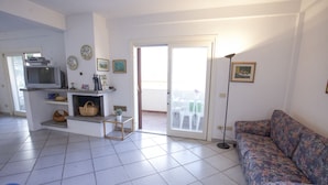 Un soggiorno con divano, televisore e zona pranzo con tavolo e sedie.