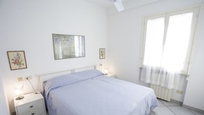 Una camera da letto con un letto, comodini, una lampada da comodino e una finestra con tende.