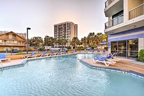 A pool area with lounge chairs and a building in the background. - Pools, Patio & Stunning Views: Myrtle Beach Oasis (Myrtle Beach)