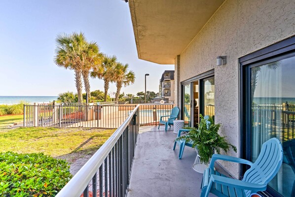 A balcony with a view of the ocean, a pool, and palm trees. - Pools, Patio & Stunning Views: Myrtle Beach Oasis (Myrtle Beach)