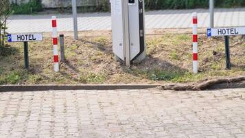 Un área de estacionamiento con estaciones de carga para vehículos eléctricos, señalizada con indicaciones y una unidad de carga.