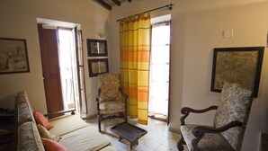 A room with a sofa, two chairs, a small table, and a window with curtains. - Appartamento La Scaletta (Capoliveri)