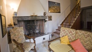 A living room with a fireplace, a sofa, a chair, and a staircase. - Appartamento La Scaletta (Capoliveri)
