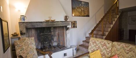 A living room with a fireplace, a sofa, a chair, and a staircase.