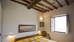 A bedroom with a bed, a chair, a painting, and a window. - Appartamento La Scaletta (Capoliveri)