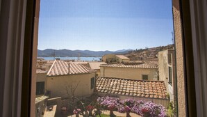 A view of terracotta-roofed buildings with a body of water and mountains in the background. - Appartamento Mono Le Fortezze (Portoferraio)