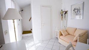 A bright, white room with a checkered sofa, a table, and a lamp. - Appartamento Mono Le Fortezze (Portoferraio)