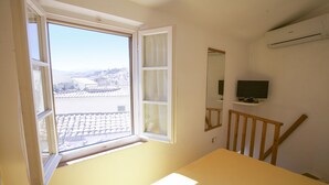 A room with a large window, a bed, a TV, and an air conditioning unit. - Appartamento Mono Le Fortezze (Portoferraio)