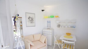A compact living space with a checkered sofa, a small white table with a yellow bowl, a white cabinet, and a framed picture on the wall. - Appartamento Mono Le Fortezze (Portoferraio)
