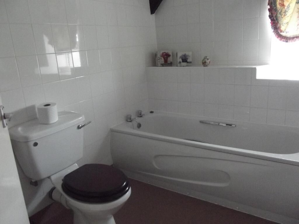 A bathroom with a toilet, a bathtub, and a window with a curtain.