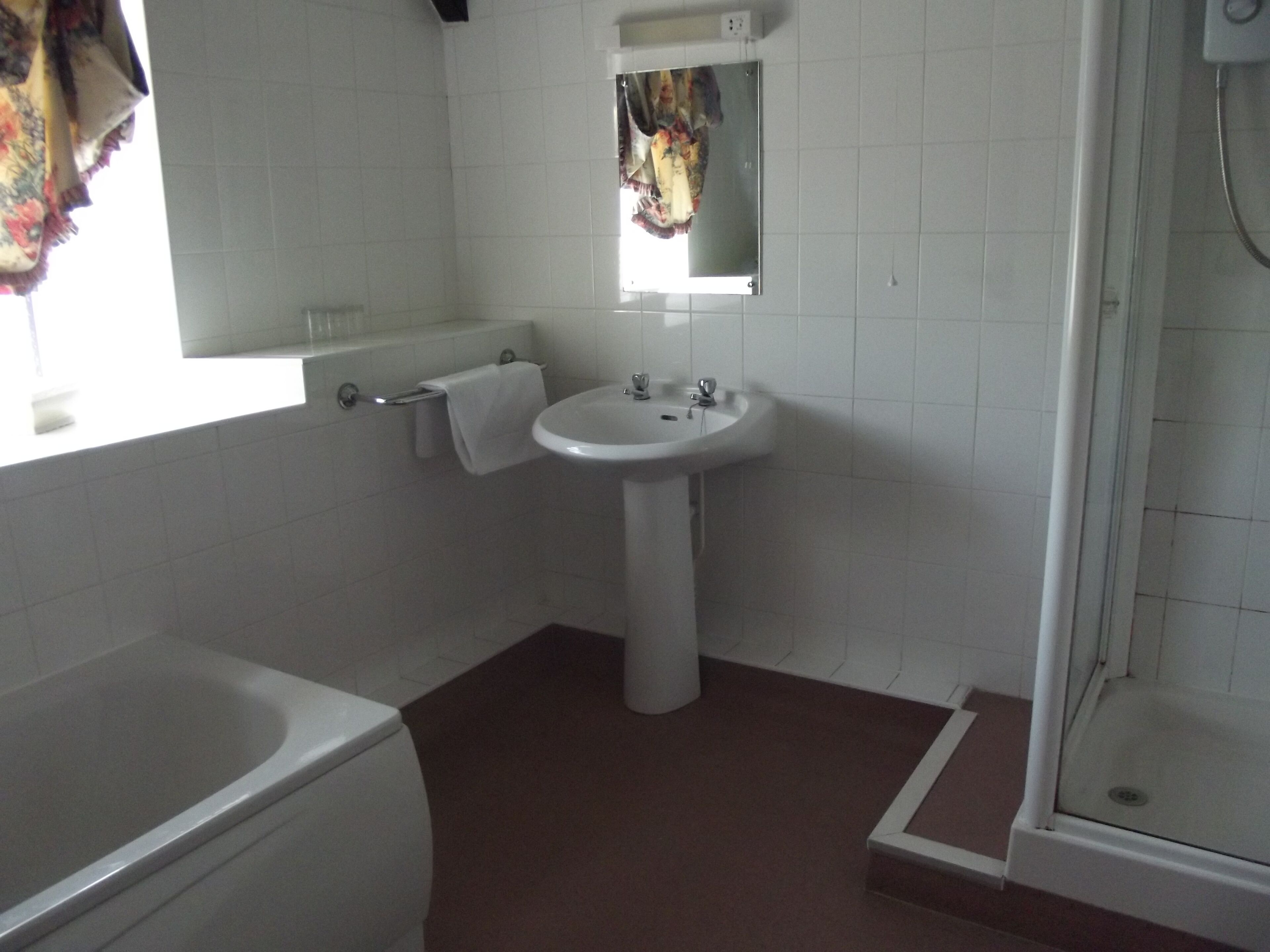 Un baño con lavamanos blanco, espejo, toallero, ducha y bañera.