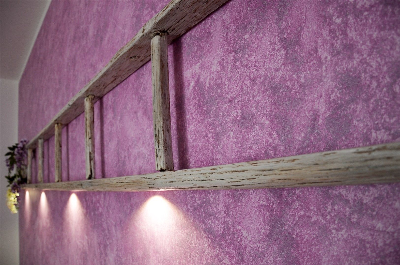 A rustic wooden beam structure against a textured purple wall.
