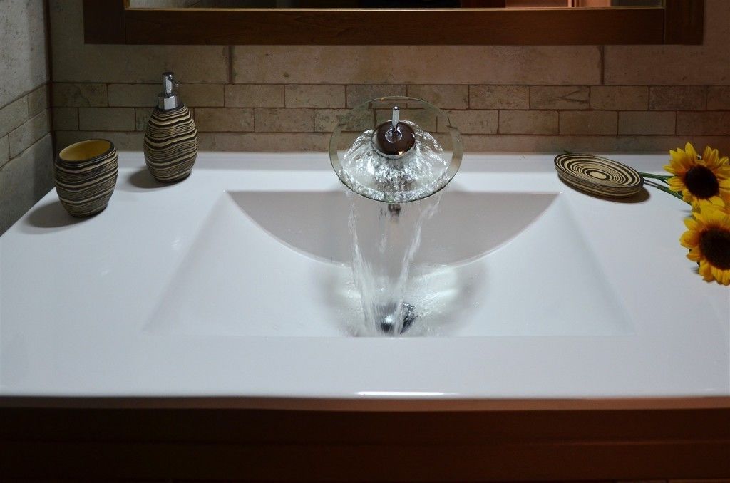 A bathroom sink with a modern faucet, a vase, and a decorative plate.