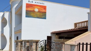 A building with a large mural of a sunset and the text "B&B ANEMOS". - B&B Anemos (Morciano di Leuca)