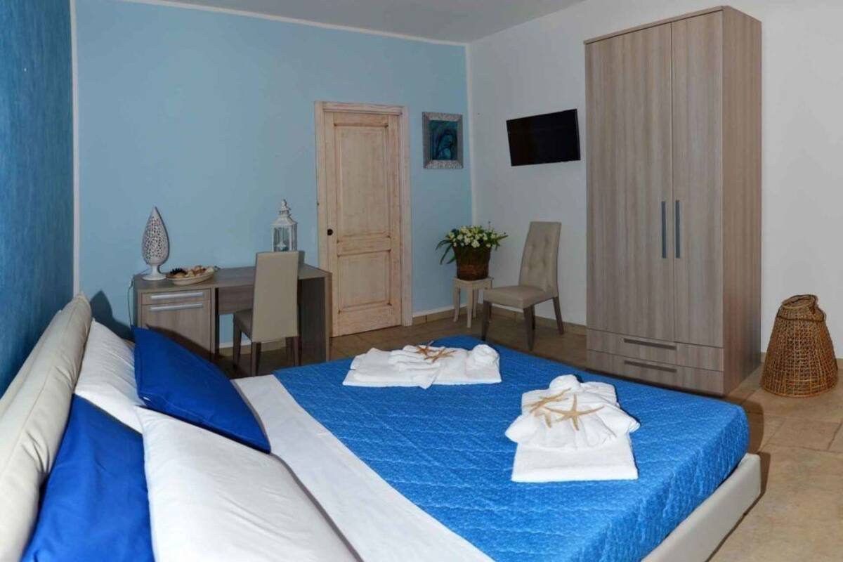 Habitación de hotel con cama, escritorio, silla, armario y televisor montado en la pared.