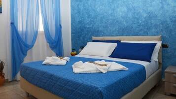 Un dormitorio con una cama, cortinas azules y una pared azul con textura.