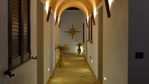 A hallway with a tiled floor, a star-shaped wall decoration, and a large archway. - B&B Anemos (Morciano di Leuca)
