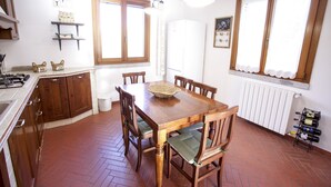 Ein Essbereich mit Holztisch und Stühlen, eine Küche mit Holzschränken und ein Weinregal.
