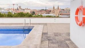 Une piscine sur le toit avec vue sur la ville, une bouée de sauvetage accrochée au mur et une bordure décorative.