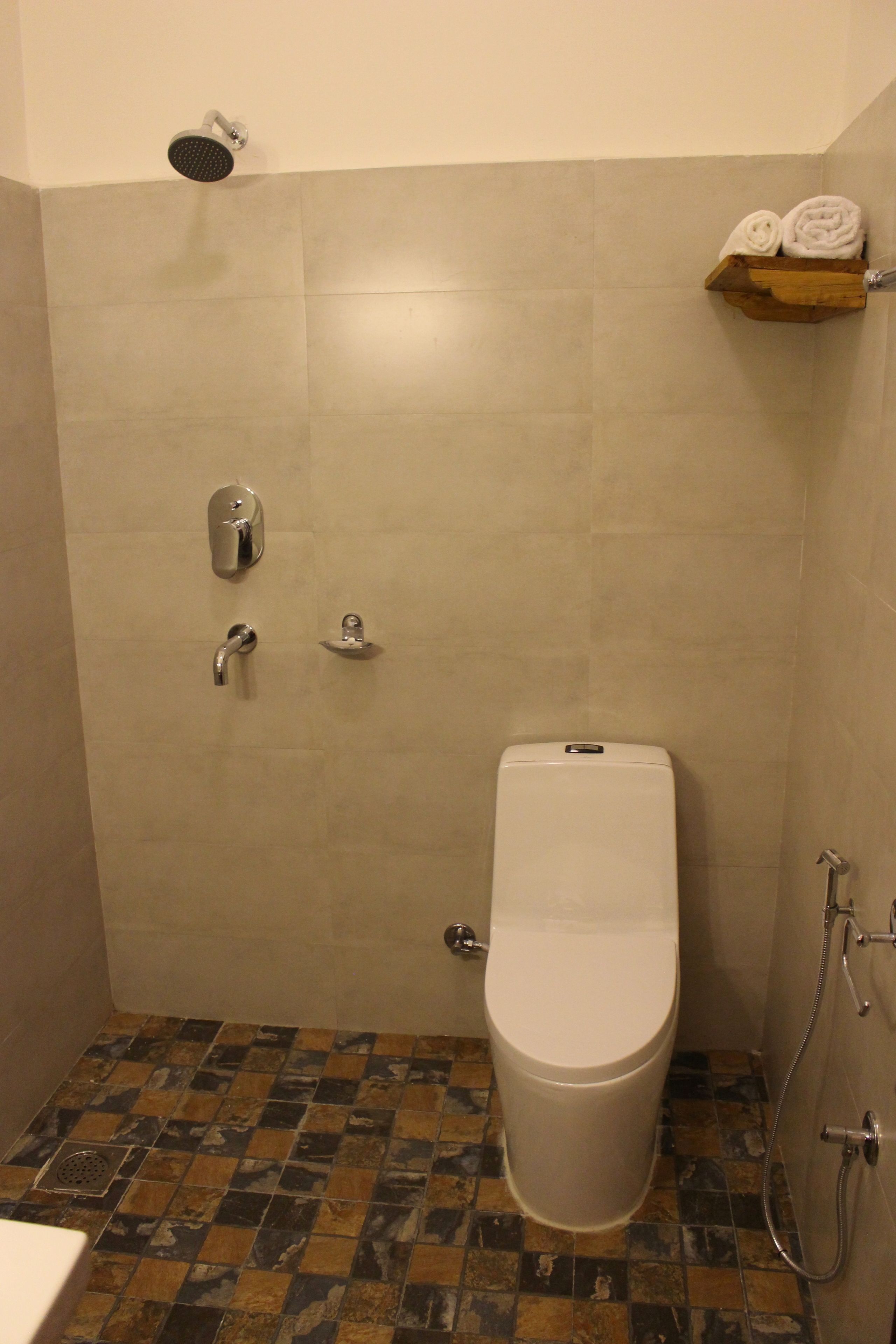A bathroom with a toilet, shower, and a shelf with towels.