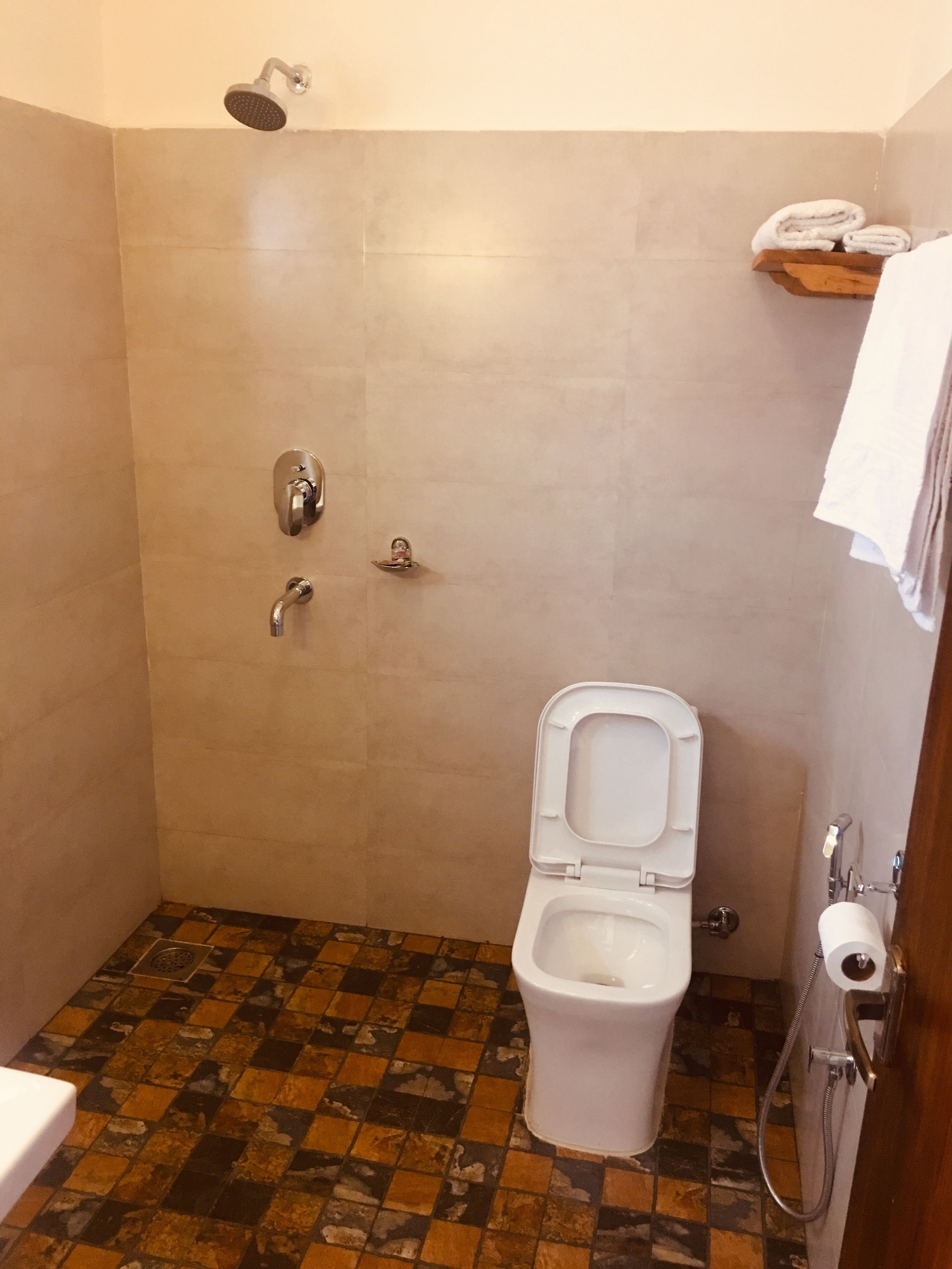 Un baño con ducha, inodoro y piso de baldosas.