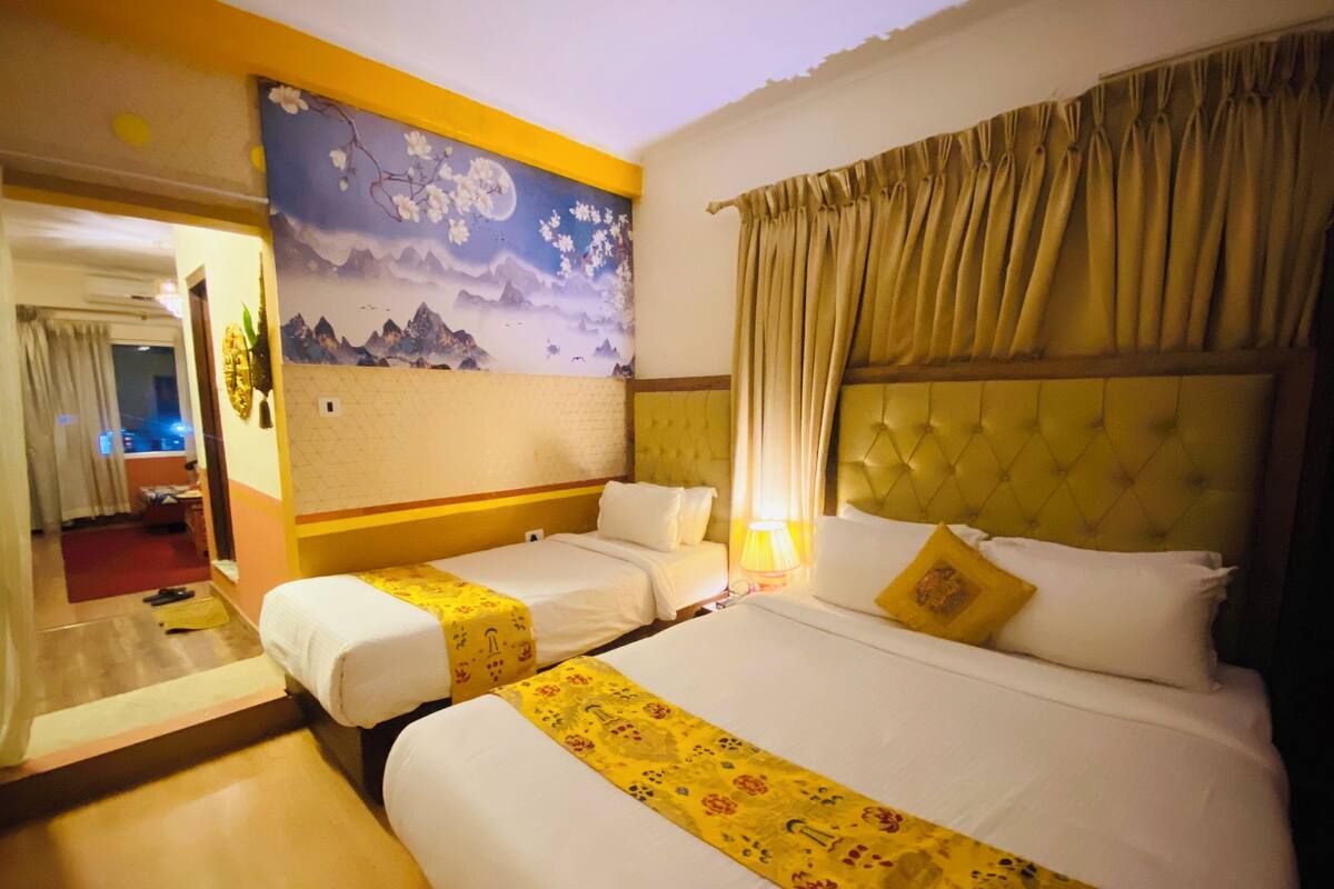 A hotel room with two beds, a mural on the wall, and a view of the outside.