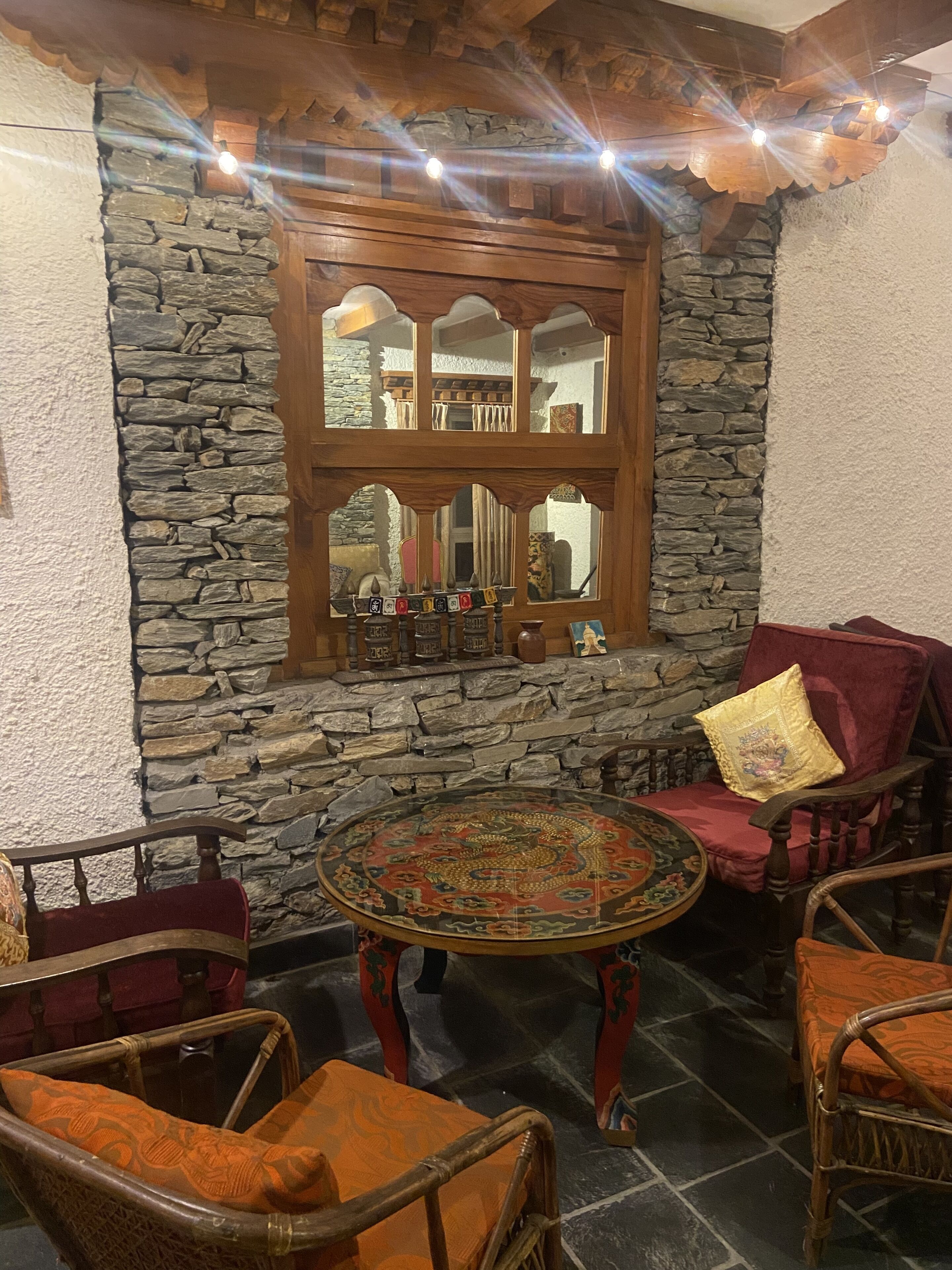 Une pièce chaleureuse avec un mur en pierre, une fenêtre en bois et une table ronde entourée de chaises.