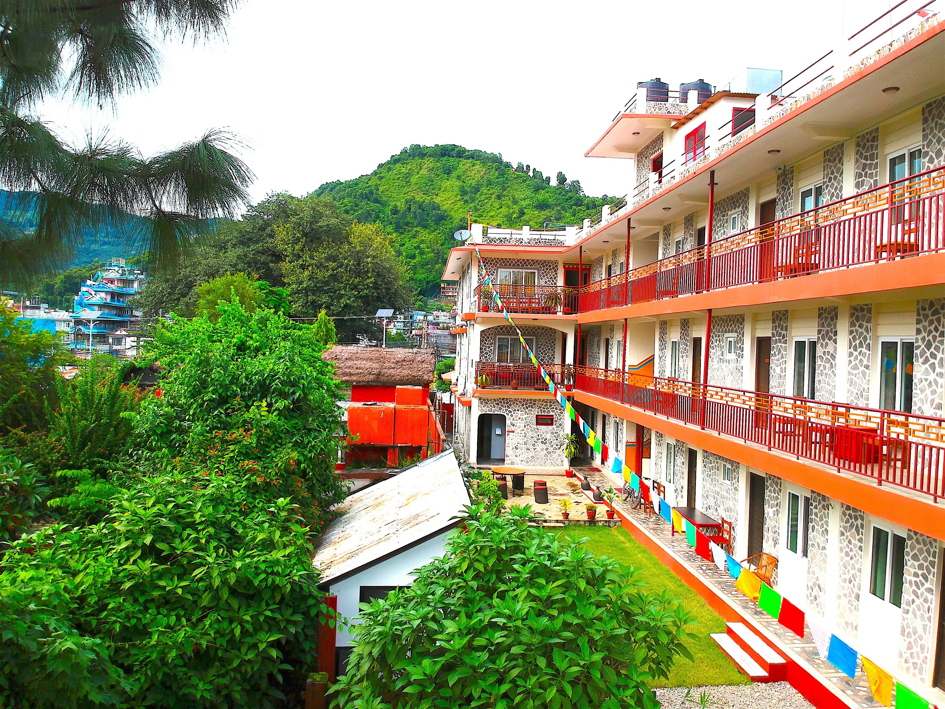 A multi-story hotel with balconies, a courtyard, and a mountainous backdrop.