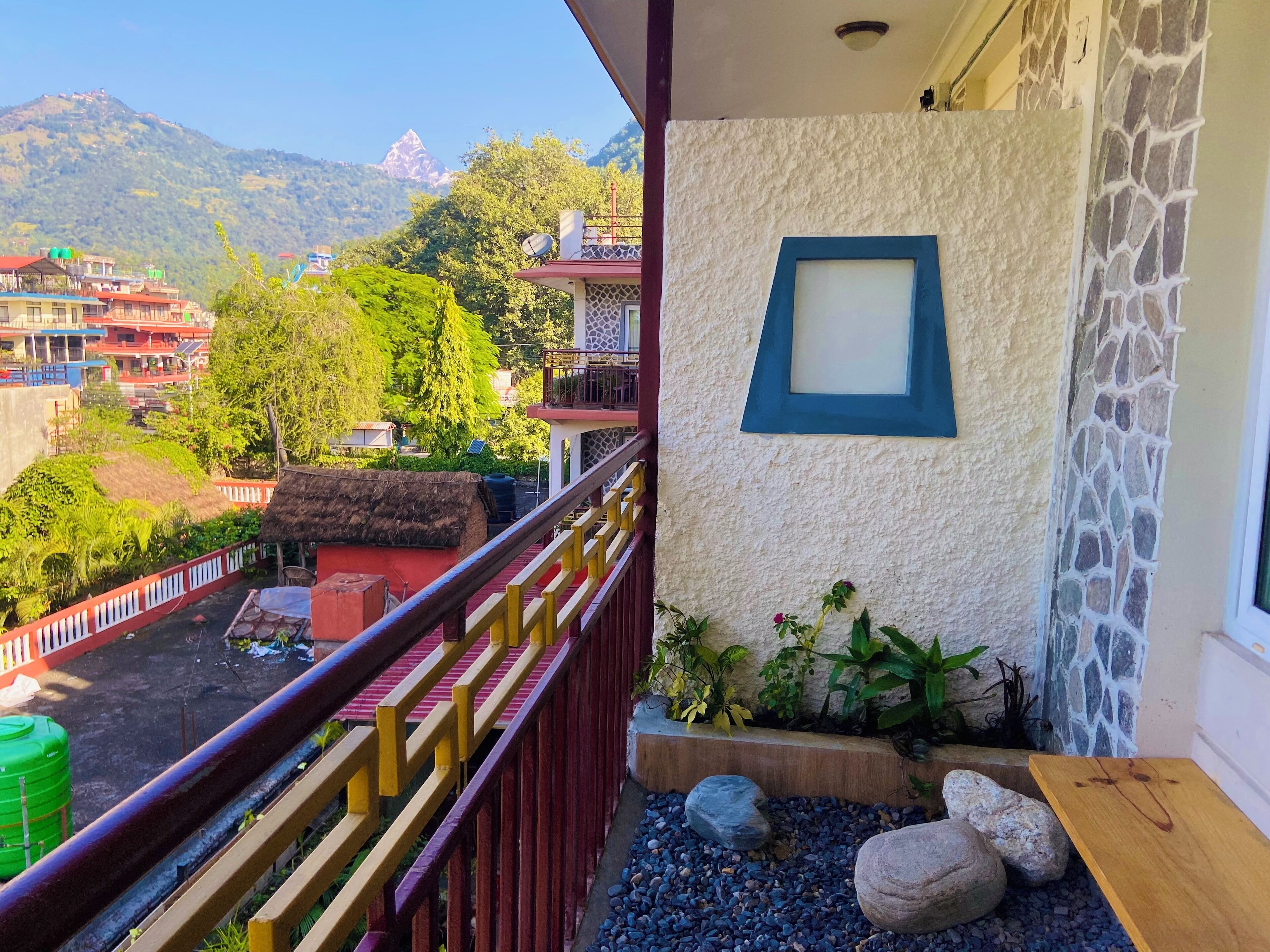 A balcony with a stone wall, a wooden bench, and a view of a mountain.
