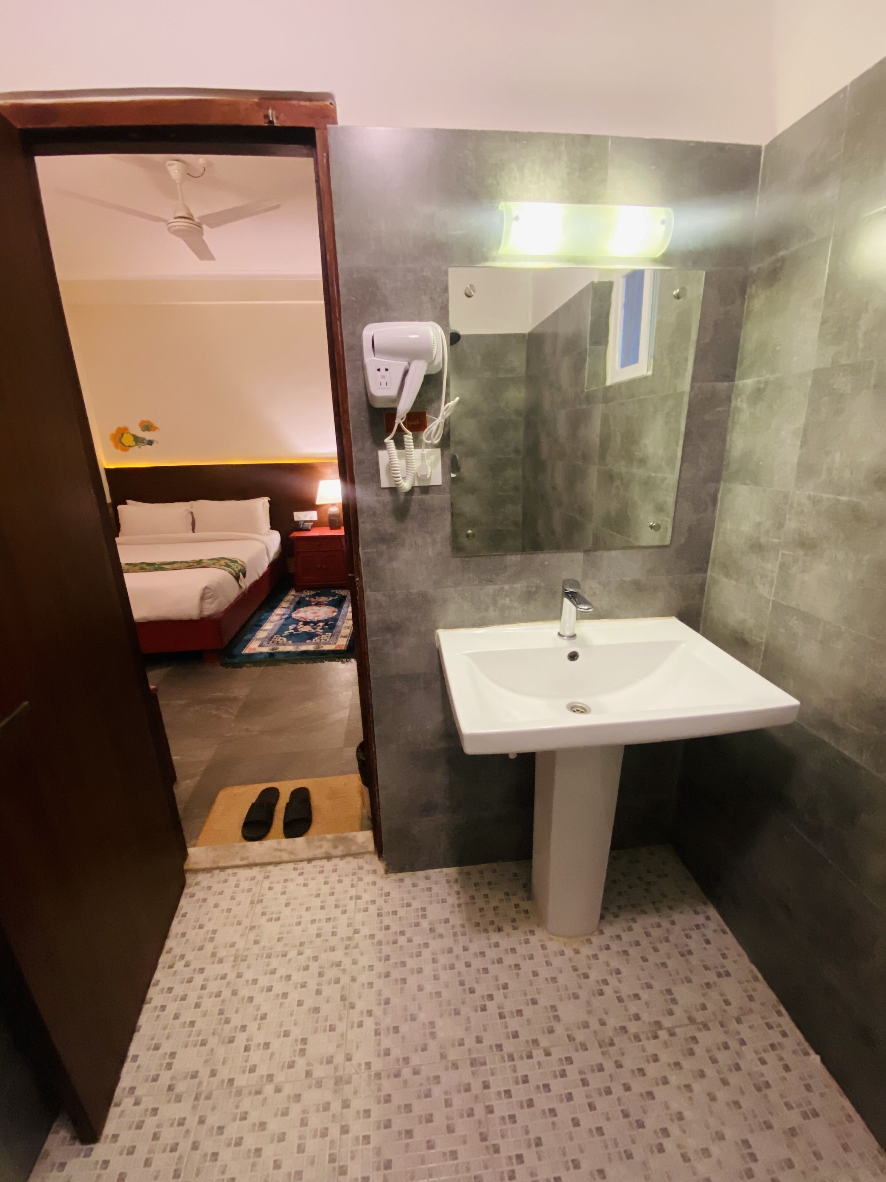 Une salle de bain avec un lavabo blanc, un miroir, un sèche-cheveux et un espace douche.