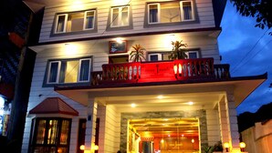 Et hotel med balkon, plantekasser og et skilt, der viser "Three Jewels Boutique Hotel".