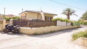 A single-story house with a tiled roof, a wooden fence, and a parked motorcycle. - Villino Laura (Portoferraio)