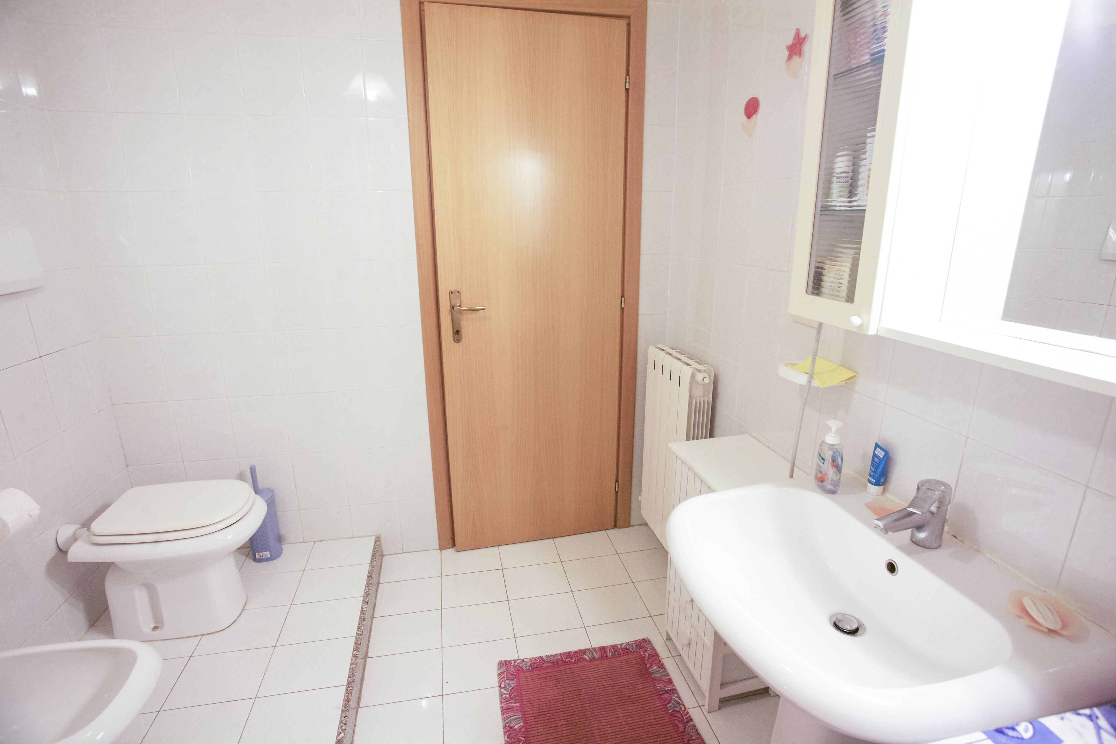 A bathroom with a toilet, sink, and a wooden door.