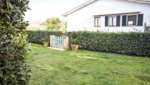 A white building with green shutters, a well-maintained garden, and a wooden gate. - Appartamento La Casina (Portoferraio)
