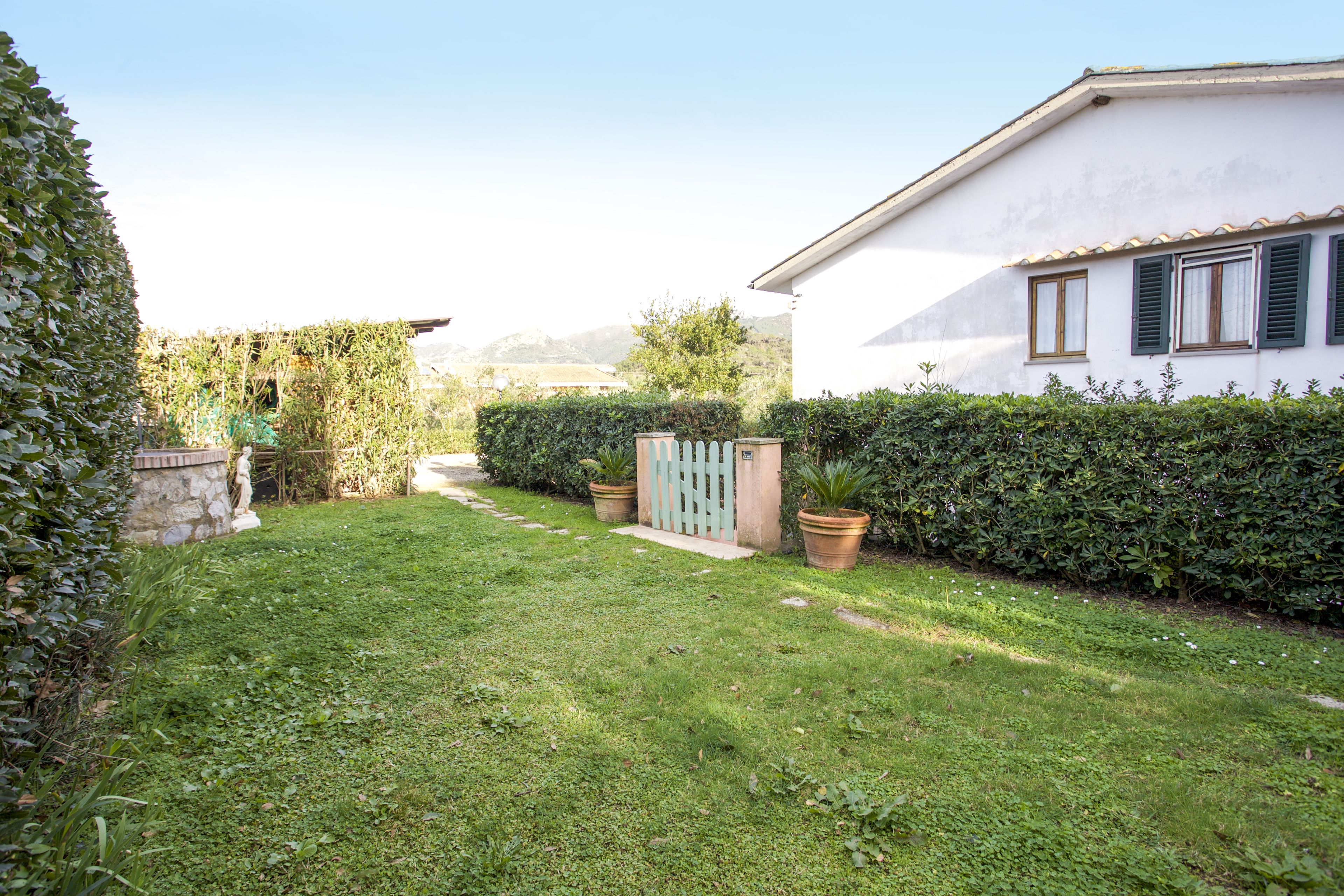 A well-maintained garden with a pathway leading to a white building with green shutters.