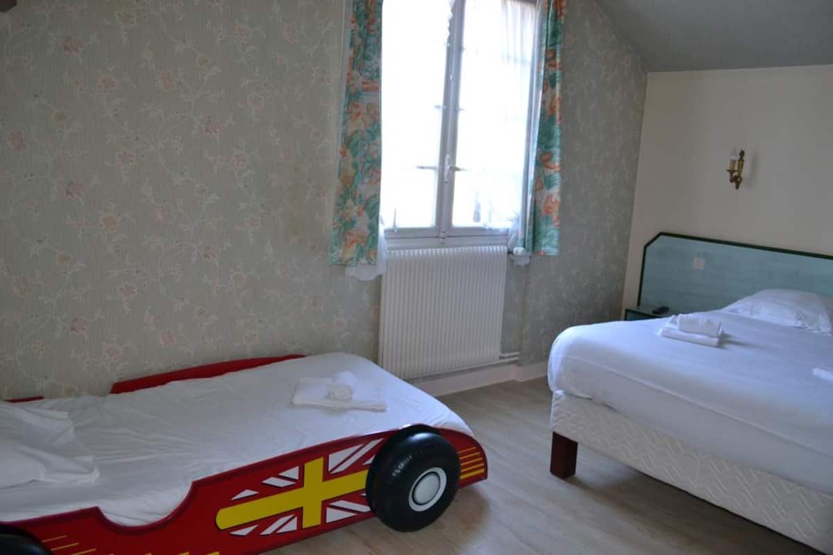 Ein Schlafzimmer mit zwei Betten, floralem Wanddesign, einem Heizkörper und einem Fenster mit Vorhängen.